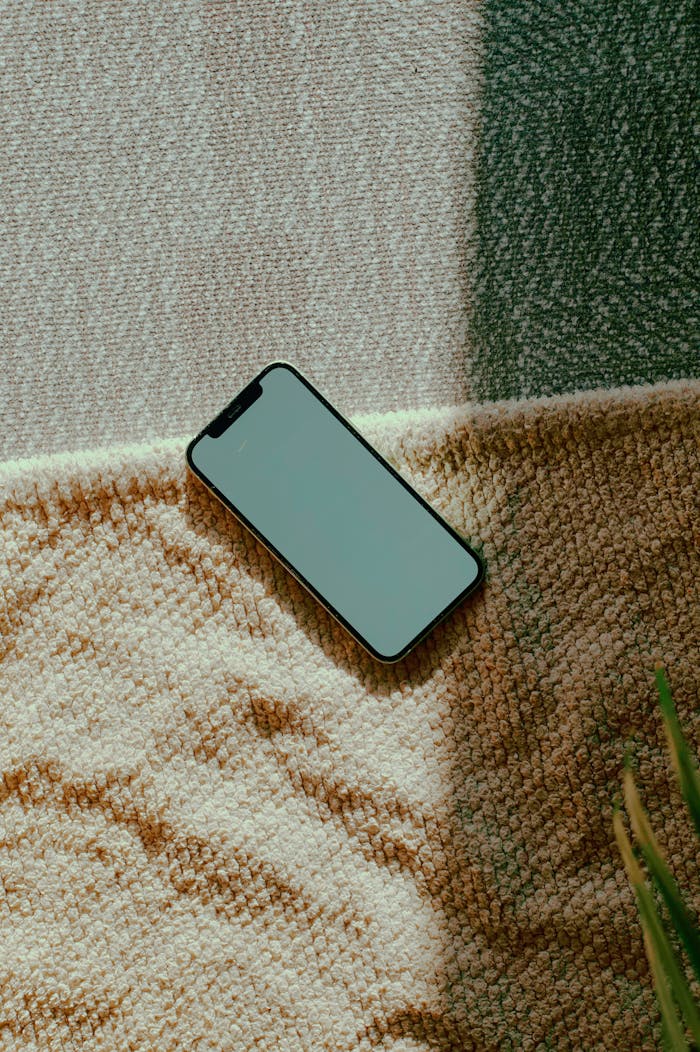 gallery-05 A smartphone rests on a textured carpet, bathed in natural sunlight, offering a warm and relaxed feel.