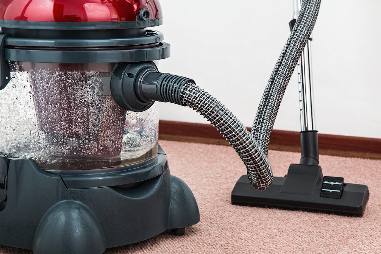 home-img Close-up of a modern vacuum cleaner with water filtration on carpet floor indoors.